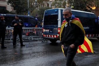 Ein Demonstrant läuft mit einer Flagge der katalonischen Separatisten an einer Polizeisperre vorbei.