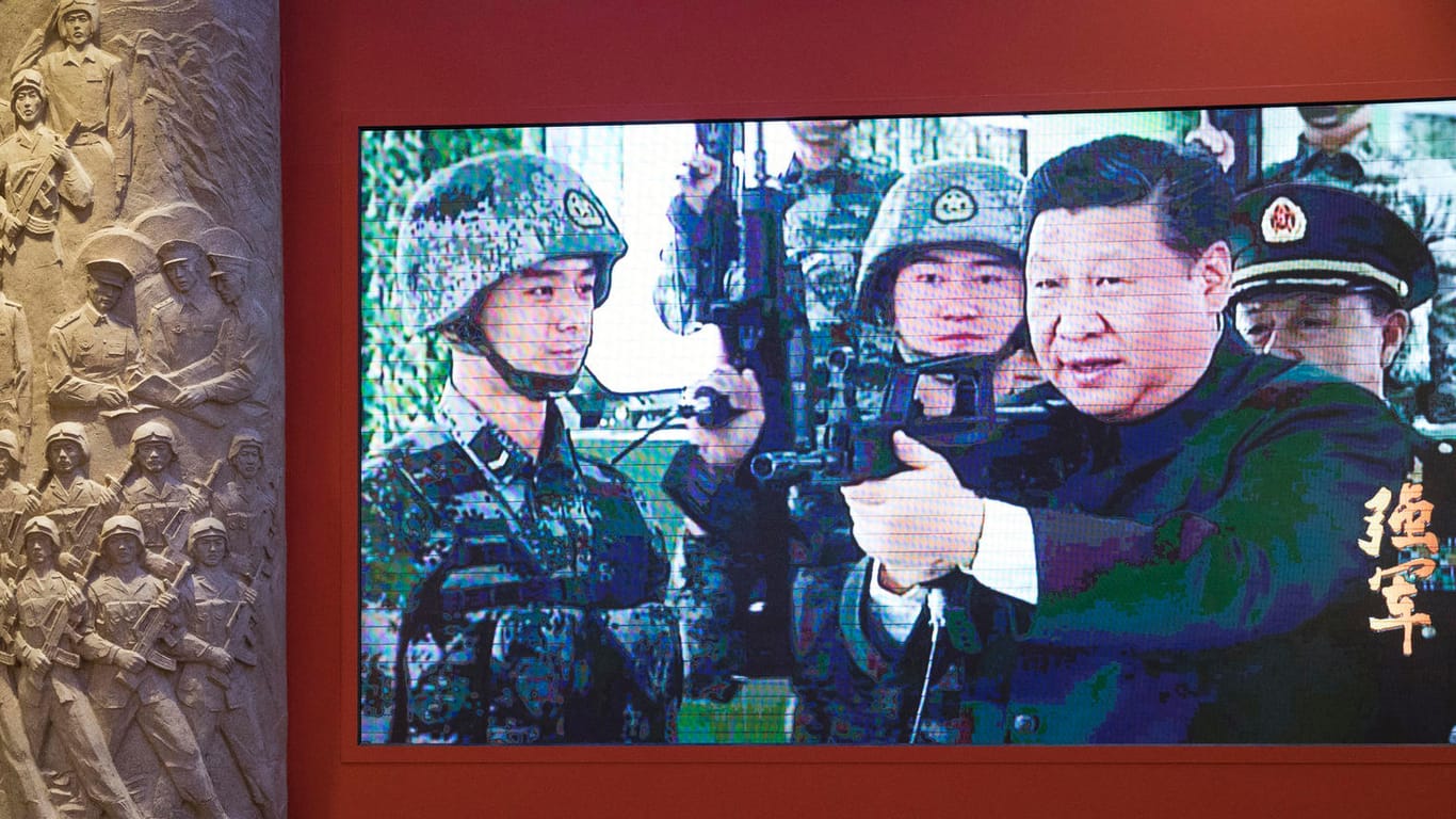 Chinas Präsident Xi ist bei einer Ausstellung in einem Video mit einem Sturmgewehr und Soldaten zu sehen.