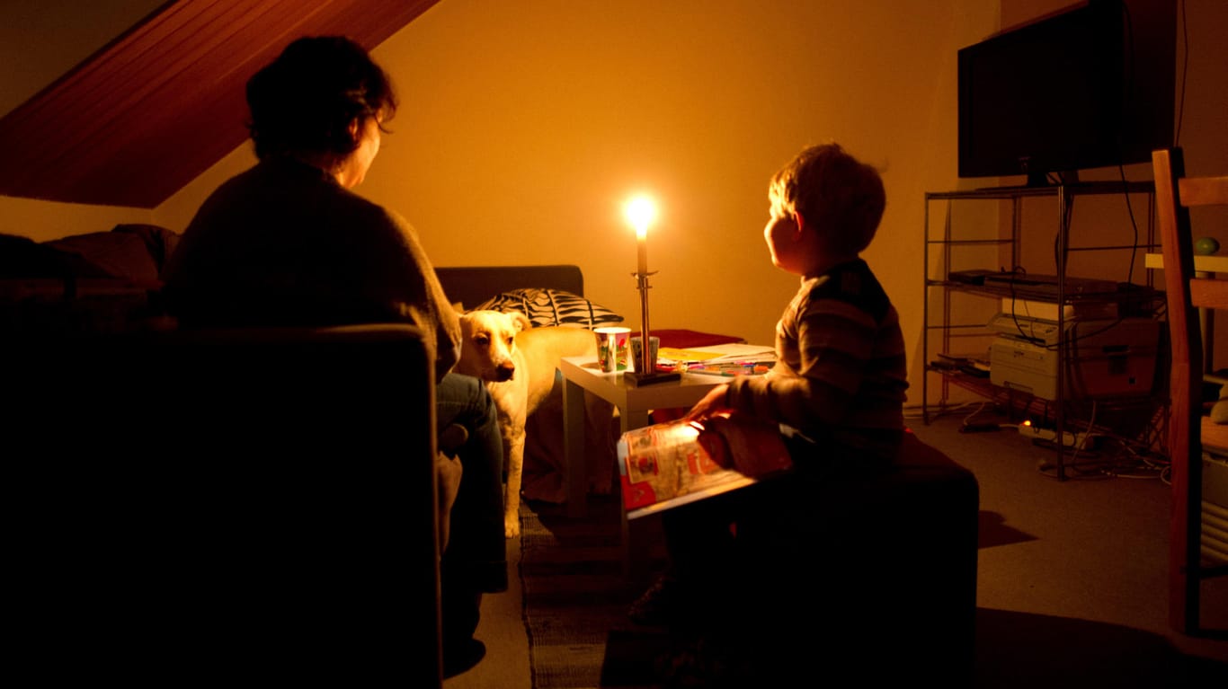 Eine Mutter sitzt am mit ihrem Sohn bei Kerzenschein in ihrer Wohnung. Der Familie wurde wegen unbezahlter Rechnungen der Strom abgestellt.