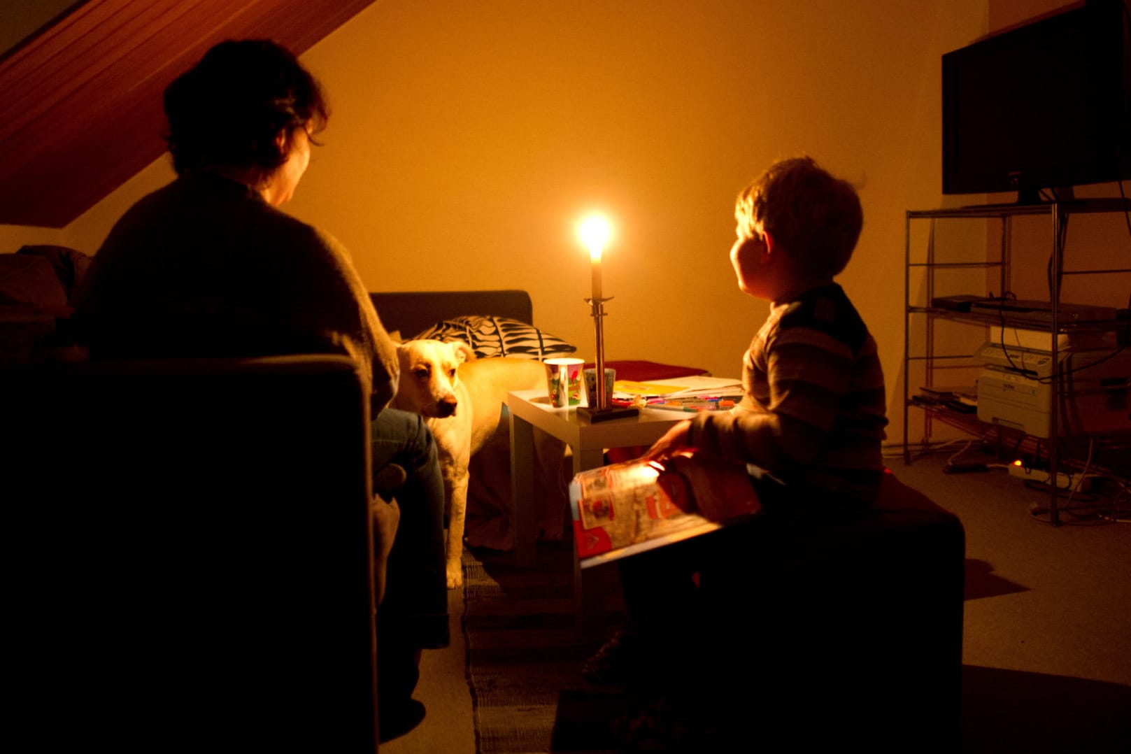 Eine Mutter sitzt am mit ihrem Sohn bei Kerzenschein in ihrer Wohnung. Der Familie wurde wegen unbezahlter Rechnungen der Strom abgestellt.