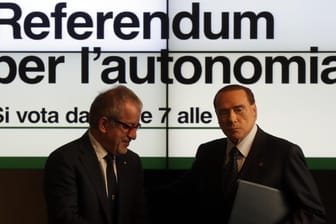 Ex-Ministerpräsident Silvio Berlusconi (r) und der Präsident der Lombardei, Roberto Maroni, stehen in Mailand während einer Pressekonferenz vor einem Plakat, welches für das Referendum wirbt.