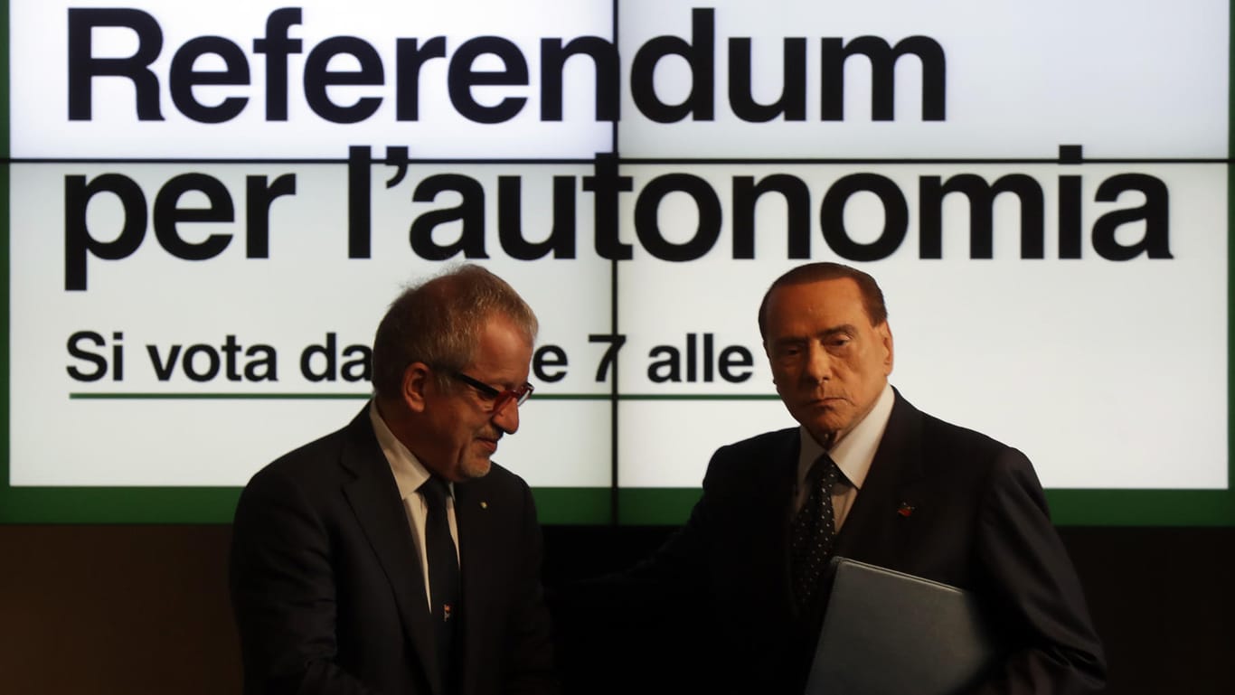 Ex-Ministerpräsident Silvio Berlusconi (r) und der Präsident der Lombardei, Roberto Maroni, stehen in Mailand während einer Pressekonferenz vor einem Plakat, welches für das Referendum wirbt.