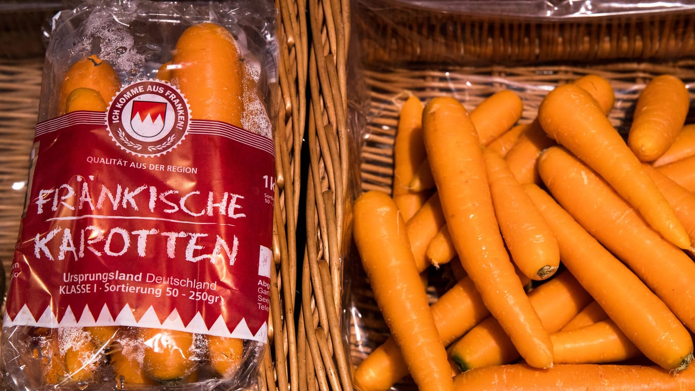 In Plastik verpackte Karotten liegen neben losen Karotten zum Verkauf
