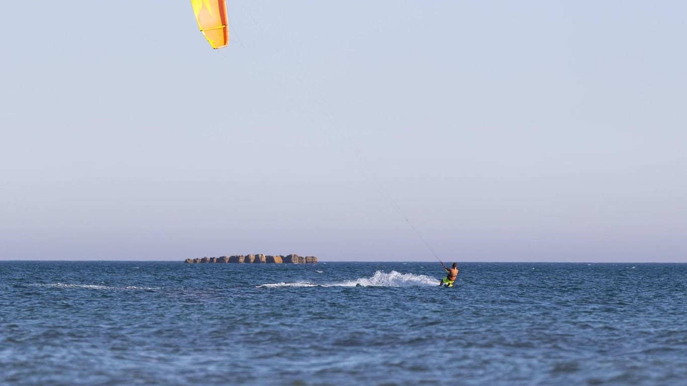 Beim Kitesurfen wird man von einem Lenkdrachen durch das Wasser gezogen.