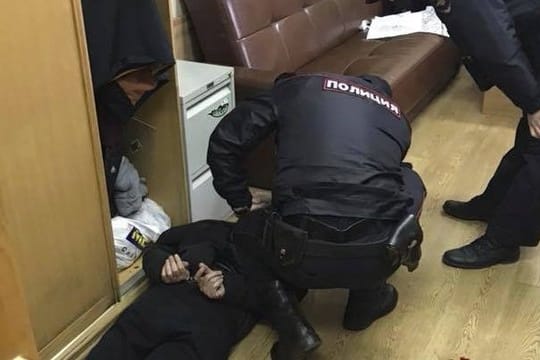 Polizisten nehmen einen Mann in der Redaktion fest.