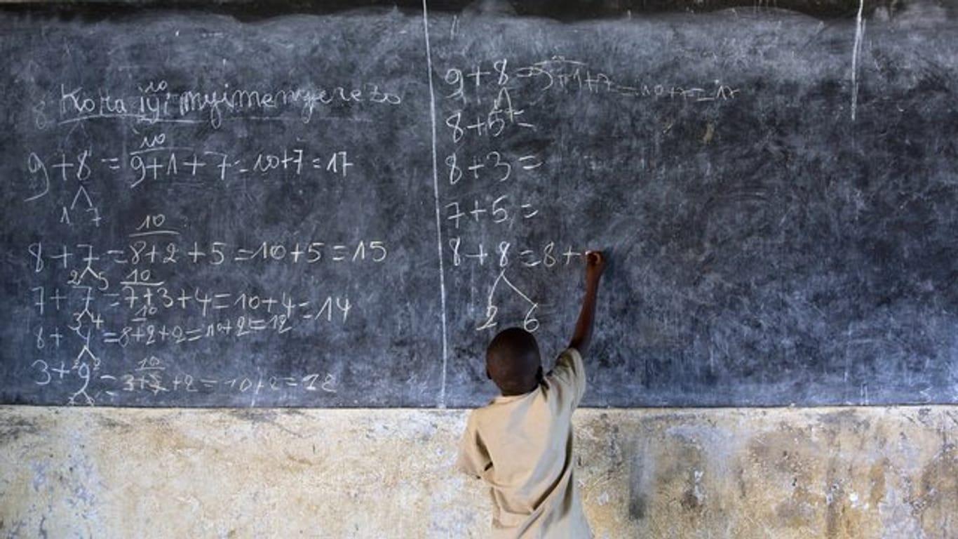 Ein Junge löst in einer Schule in Burundi an der Tafel Mathematikaufgaben.