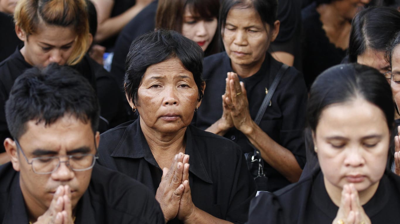 Trauernde Thais knien am Wegesrand der Zeremonie.