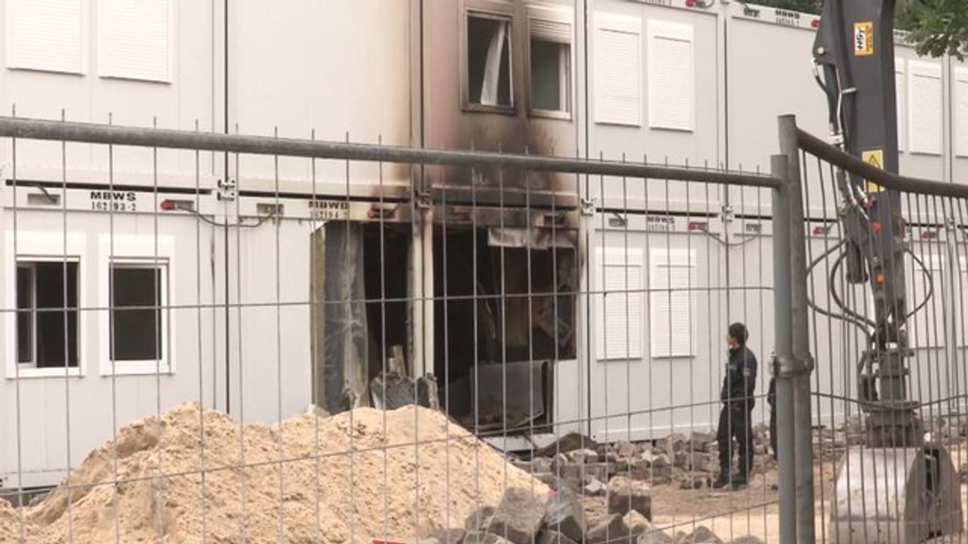 Polizeibeamte untersuchen in Bremen ausgebrannte Wohncontainer.