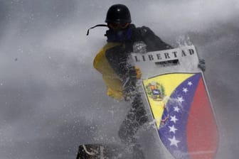 Ein Demonstrant in Venezuela sucht Schutz hinter einem selbstgemachten Schild.