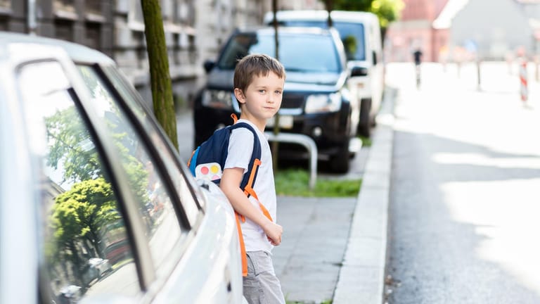 Ein Schulkind betritt hinter einem Auto eine Straße: Kindern fällt es mitunter schwer, die Geschwindigkeit eines herannahendes Autos einzuschätzen.