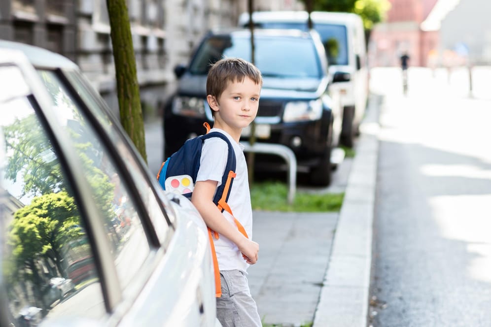 Ein Schulkind betritt hinter einem Auto eine Straße: Kindern fällt es mitunter schwer, die Geschwindigkeit eines herannahendes Autos einzuschätzen.
