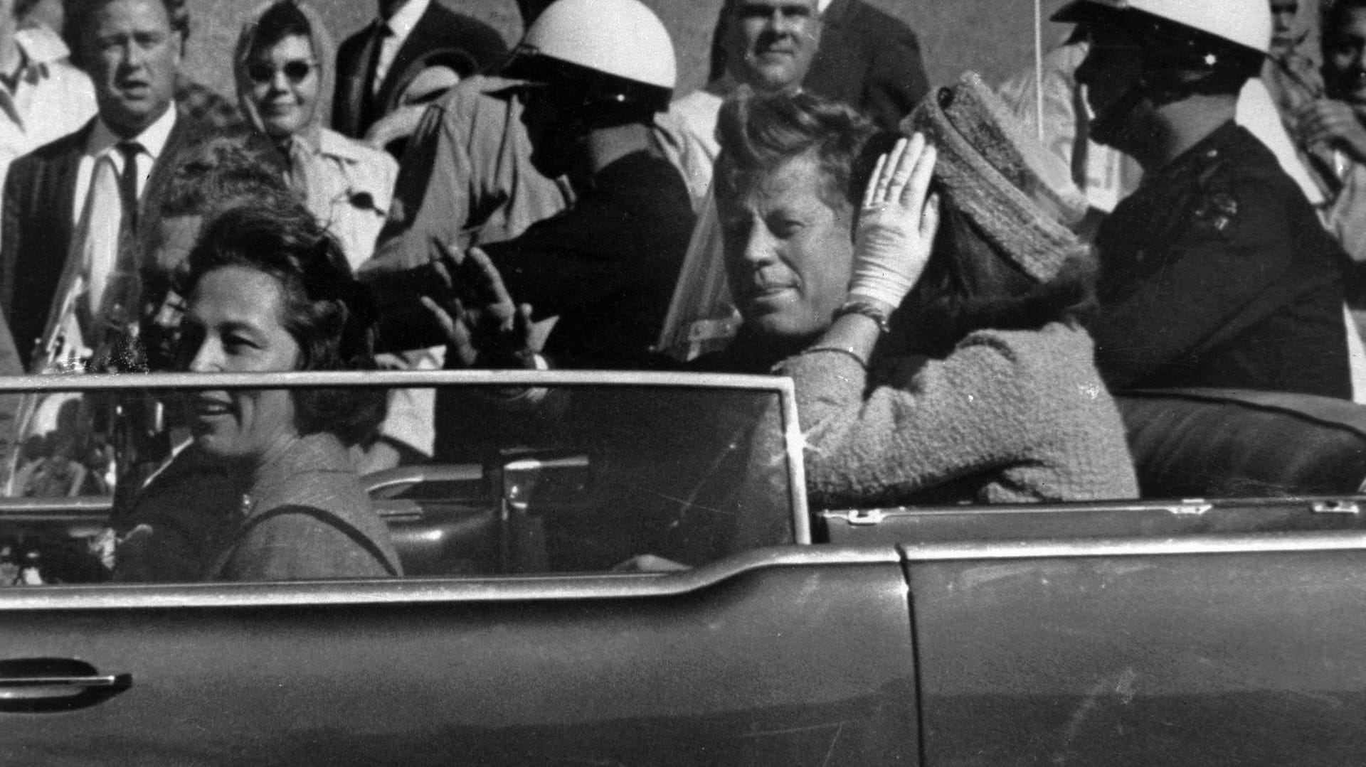 Kurz vor seiner Ermordung sitzt der damalige US-Präsident John F. Kennedy in Dallas zusammen mit seiner Frau Jacqueline (r), Nellie Connally (l) und ihrem Mann, dem Gouverneur von Texas, John Connally, in einer offenen Limousine.