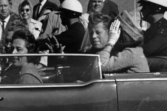 Kurz vor seiner Ermordung sitzt der damalige US-Präsident John F. Kennedy in Dallas zusammen mit seiner Frau Jacqueline (r), Nellie Connally (l) und ihrem Mann, dem Gouverneur von Texas, John Connally, in einer offenen Limousine.