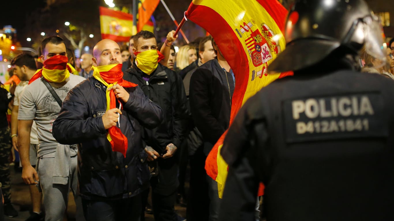 Gegner der Unabhängigkeit geraten in Barcelona mit Polizisten aneinander. Einige Demonstranten haben sich mit der spanischen Flagge vermummt.