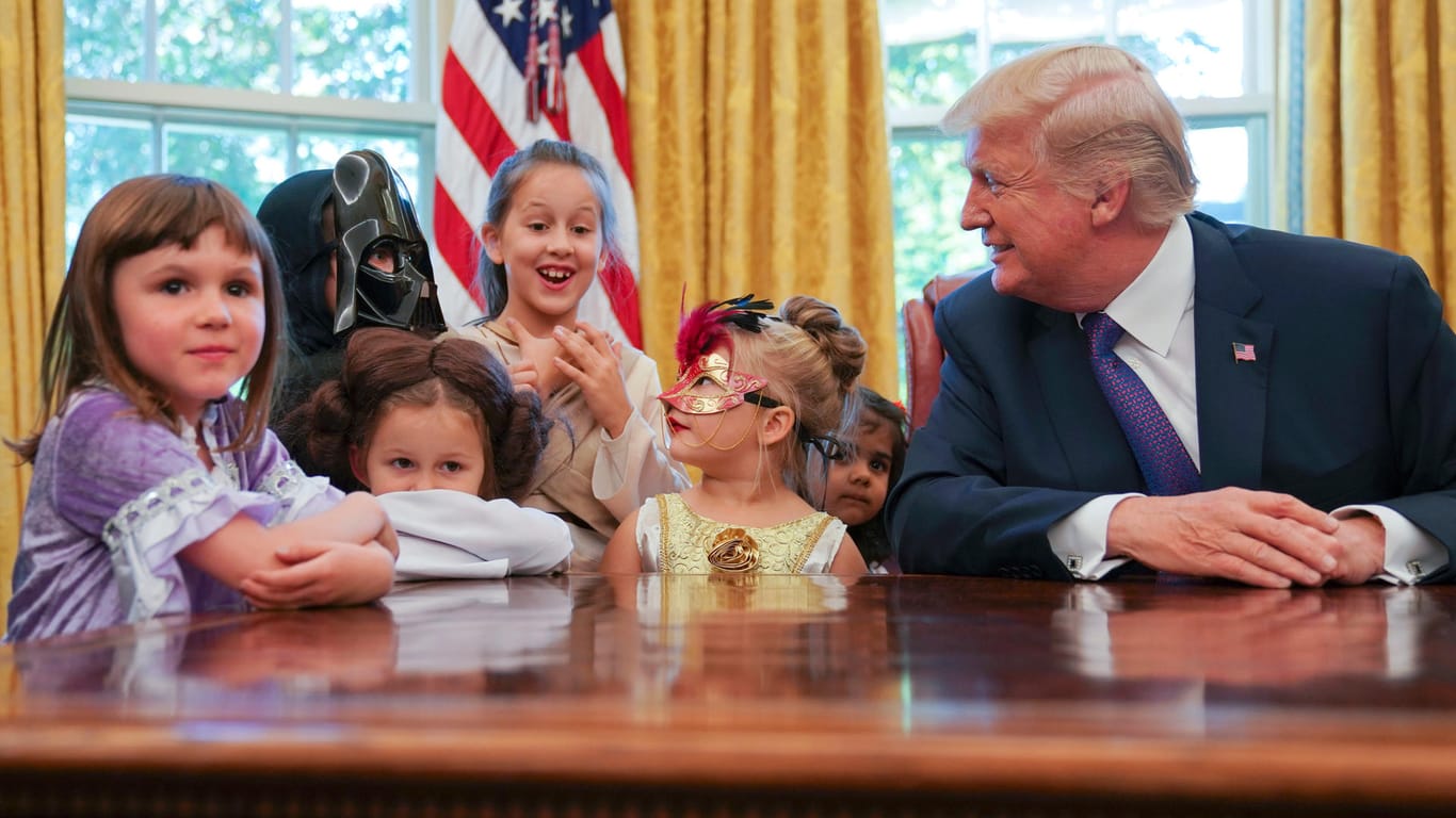 Donald Trump verteilt Schokolade an Kinder.
