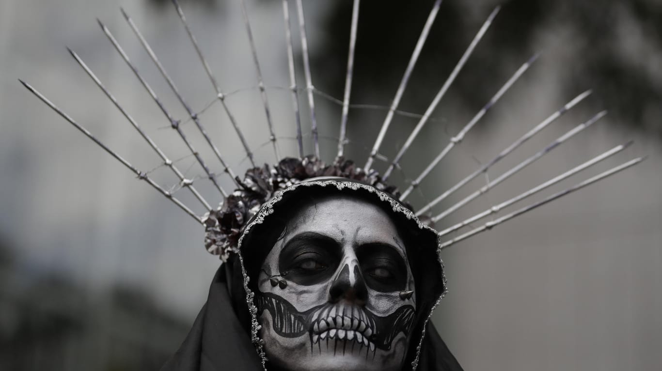 Eine verkleidete Frau wartet in Mexiko-Stadt auf den Beginn der Prozession.