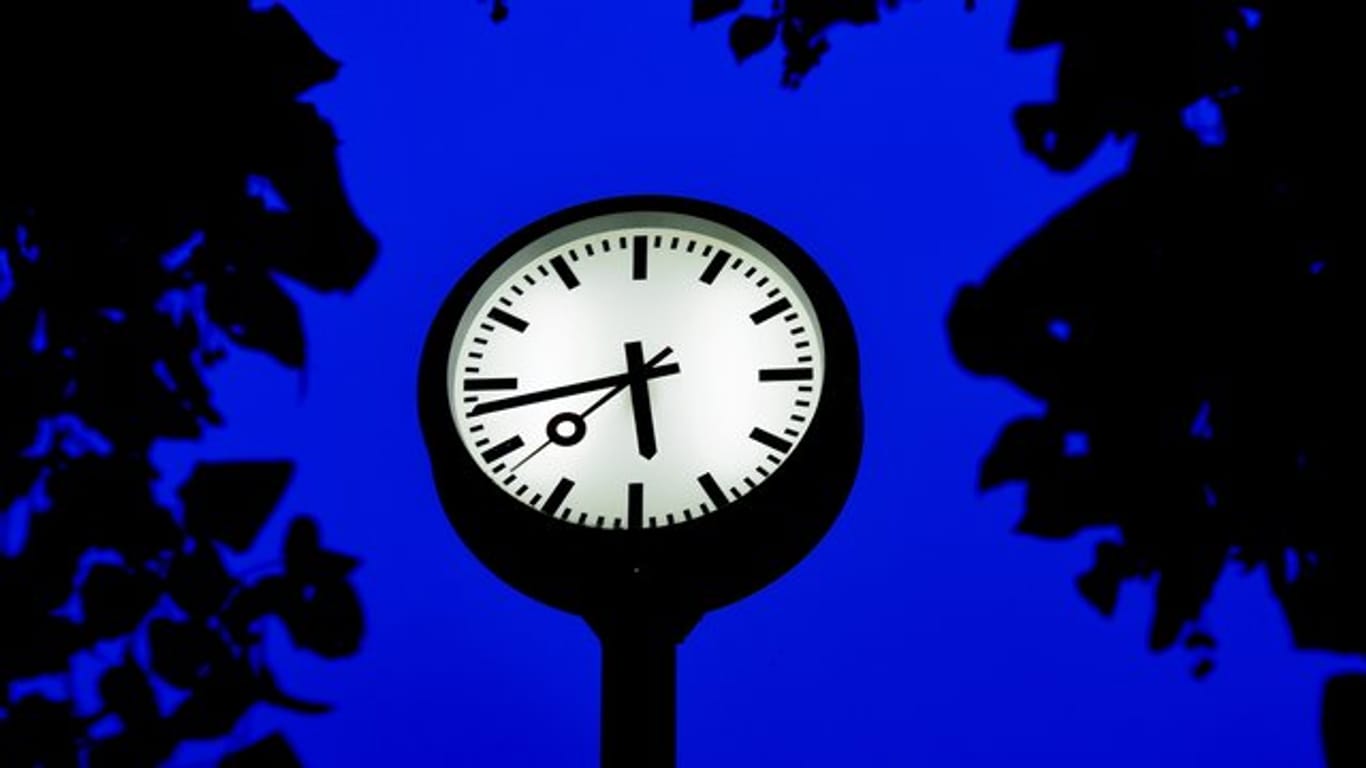 Eine Uhr steht zur blauen Stunde auf dem Zeitfeld in Düsseldorf.