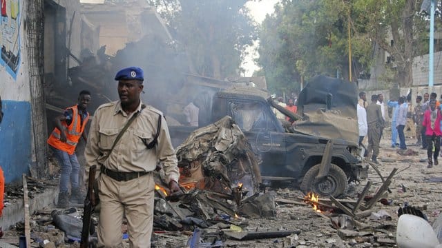 Ein somalischer Soldat in Mogadischu vor von einer Explosion zerstörten Fahrzeugen. Ein somalischer Soldat in Mogadischu vor von einer Explosion zerstörten Fahrzeugen.