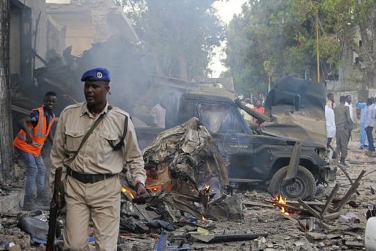 Ein somalischer Soldat in Mogadischu vor von einer Explosion zerstörten Fahrzeugen.
