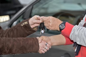 Zwei Menschen geben sich die Hand und tauchen parallel einen Autoschlüssel