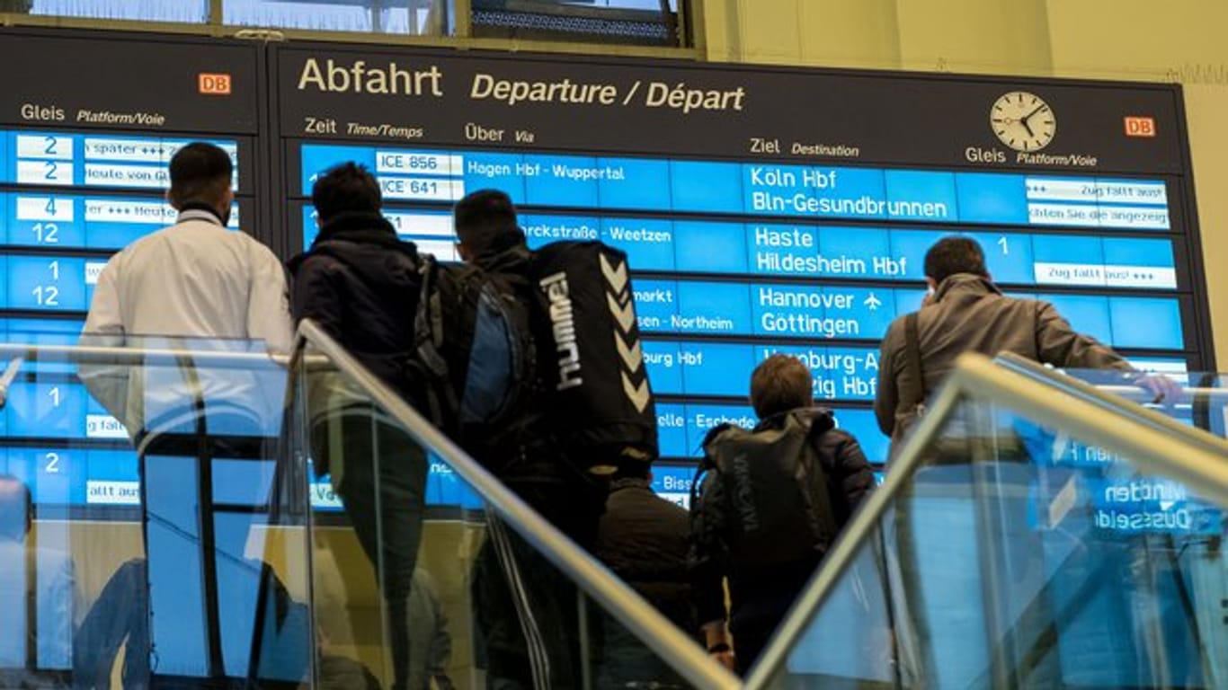 Zugreisende stehen am Sonntag vor einer Anzeigetafel auf dem Hauptbahnhof in Hannover und warten auf eine Verbindung.