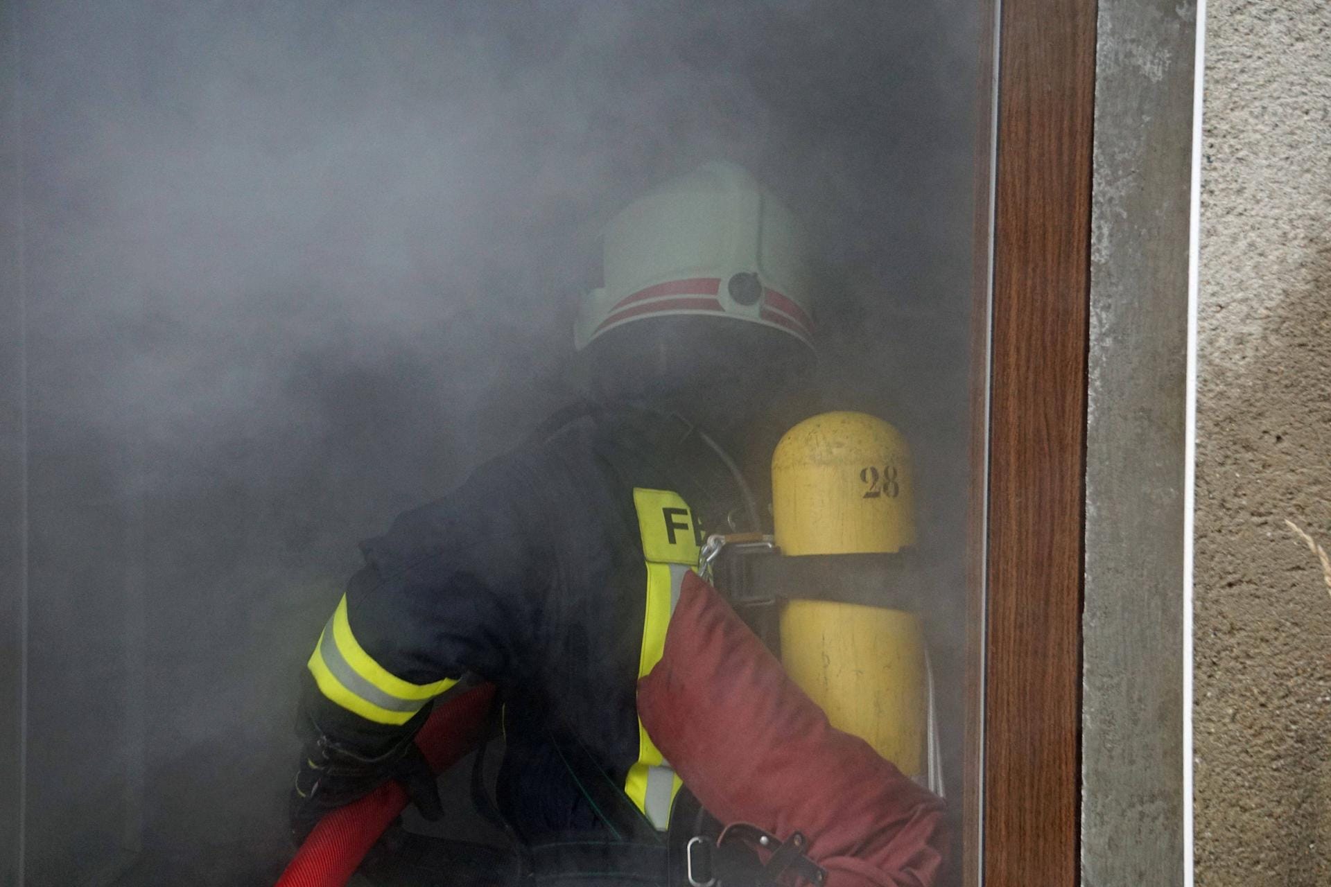 Feuerwehrmann mit Atemschutz betritt ein Haus voller Rauch