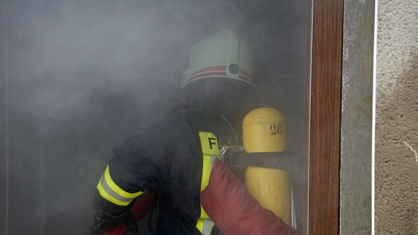 Feuerwehrmann mit Atemschutz betritt ein Haus voller Rauch
