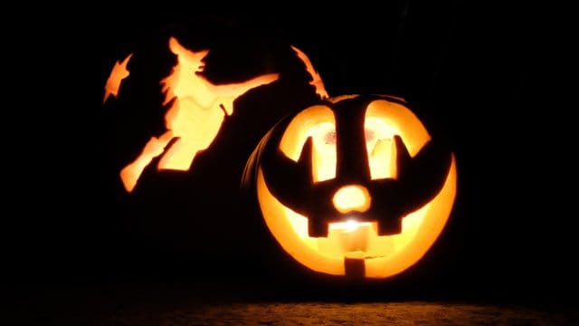 Zwei mit Kerzen von innen beleuchtete Halloween-Kürbisse vor einem Privathaus in Stuttgart.