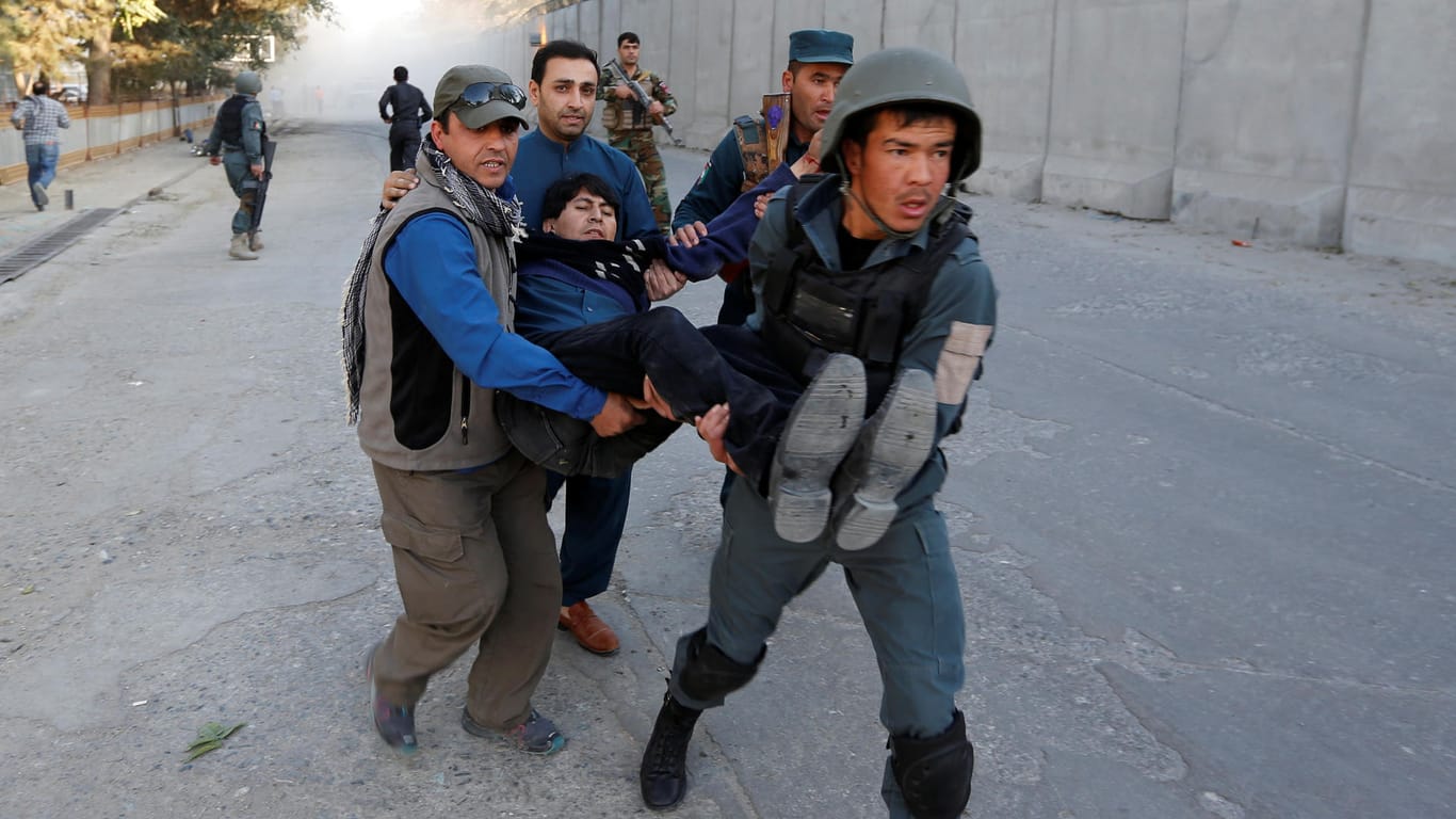 Polizisten und Helfer tragen einen verletzten Mann vom Ort der Explosion im Diplomatenviertel von Kabul weg.