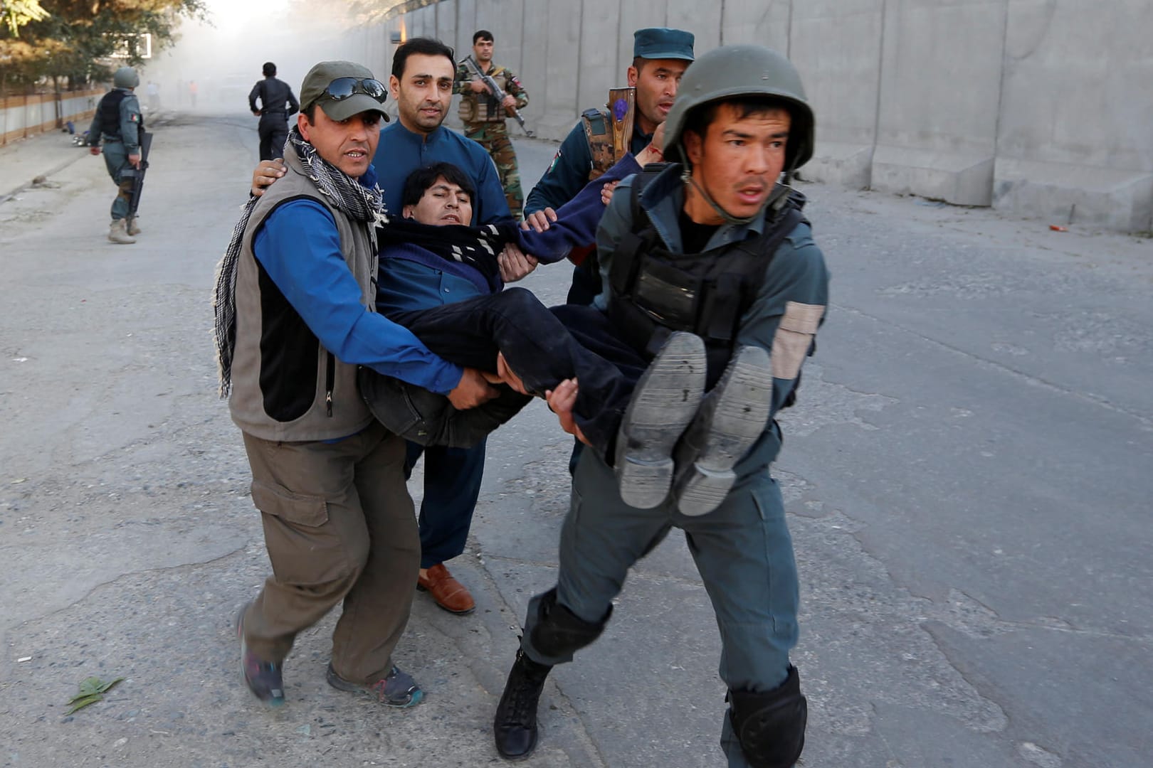 Polizisten und Helfer tragen einen verletzten Mann vom Ort der Explosion im Diplomatenviertel von Kabul weg.