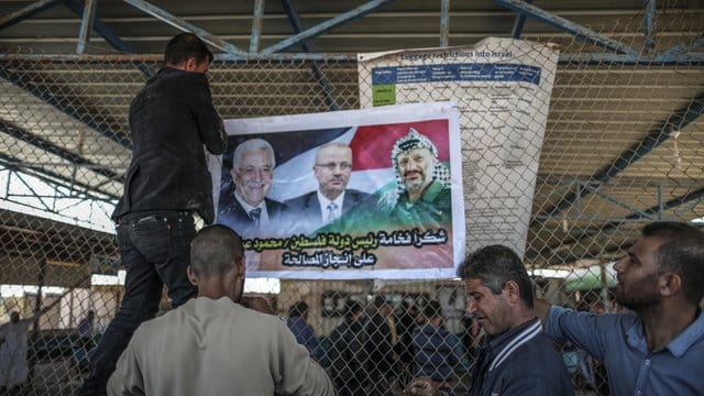 Männer bringen am israelisch-palästinischen Grenzübergang Erez ein Poster mit den Porträts von Palästinenserpräsident Mahmud Abbas (l), Premierminister Rami Hamdallah (M) und dem verstorbenen Palästinenserführer Yasser Arafat an. Männer bringen am israelisch-palästinischen Grenzübergang Erez ein Poster mit den Porträts von Palästinenserpräsident Mahmud Abbas (l), Premierminister Rami Hamdallah (M) und dem verstorbenen Palästinenserführer Yasser Arafat an.