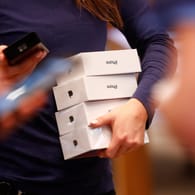 Eine Mitarbeiterin im Berliner Apple-Store trägt mehrere iPhone X-Verpackungen unterm Arm