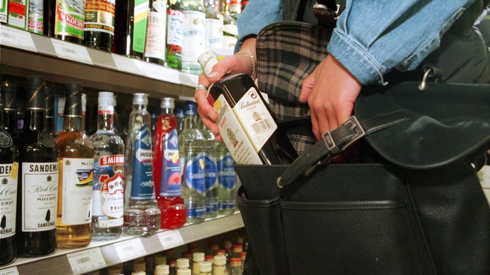 Ladendiebin beim Diebstahl einer Flasche Alkohol im Supermarkt