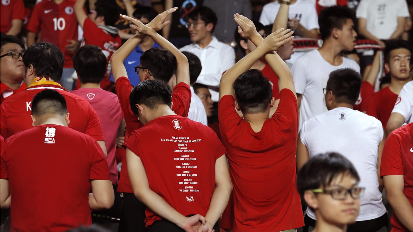 Einige Fans der Fußballnationalmannschaft von Hongkong drehen sich am 10.10.2017 in Hongkong (China) vor ihrem Qualifikationsspiel gegen Malaysia für die Fußball-Asienmeisterschaft um, während die chinesische Nationalhymne gespielt wird.