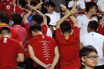 Einige Fans der Fußballnationalmannschaft von Hongkong drehen sich am 10.10.2017 in Hongkong (China) vor ihrem Qualifikationsspiel gegen Malaysia für die Fußball-Asienmeisterschaft um, während die chinesische Nationalhymne gespielt wird.