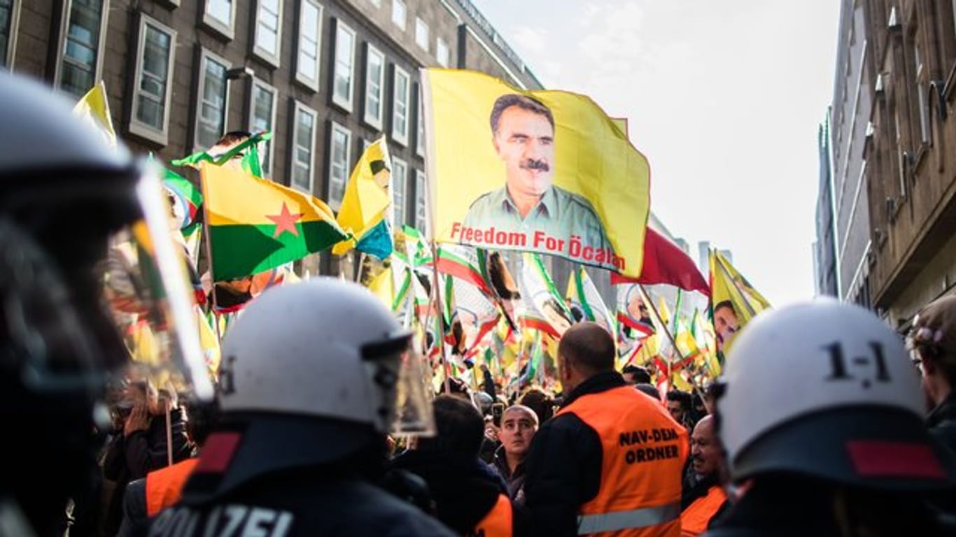 Polizisten blockieren eine Kurden-Demonstration in Düsseldorf, bei der verbotene Fahnen von Öcalan geschwenkt werden.