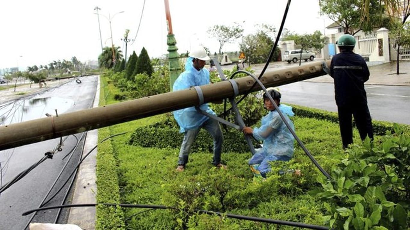 Arbeiter reparieren in Hanoi einen Strommast, der vom Sturm umgeworfen wurde.