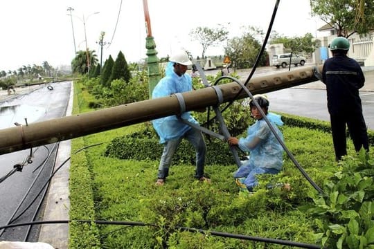 Arbeiter reparieren in Hanoi einen Strommast, der vom Sturm umgeworfen wurde.
