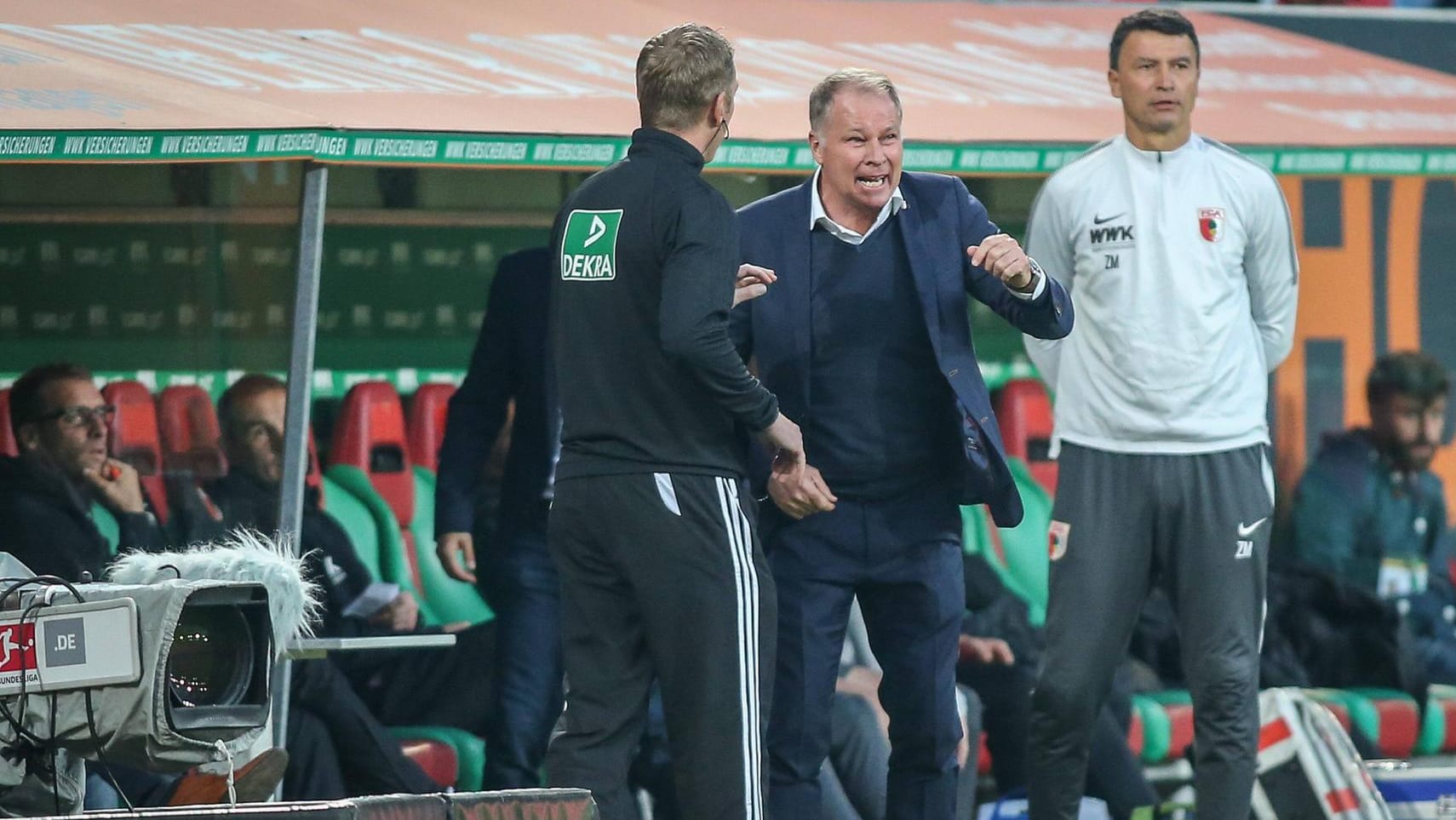 Augsburgs Geschäftsführer Stefan Reuter (m.) im Gespräch mit dem Schiedsrichter-Assistenten.