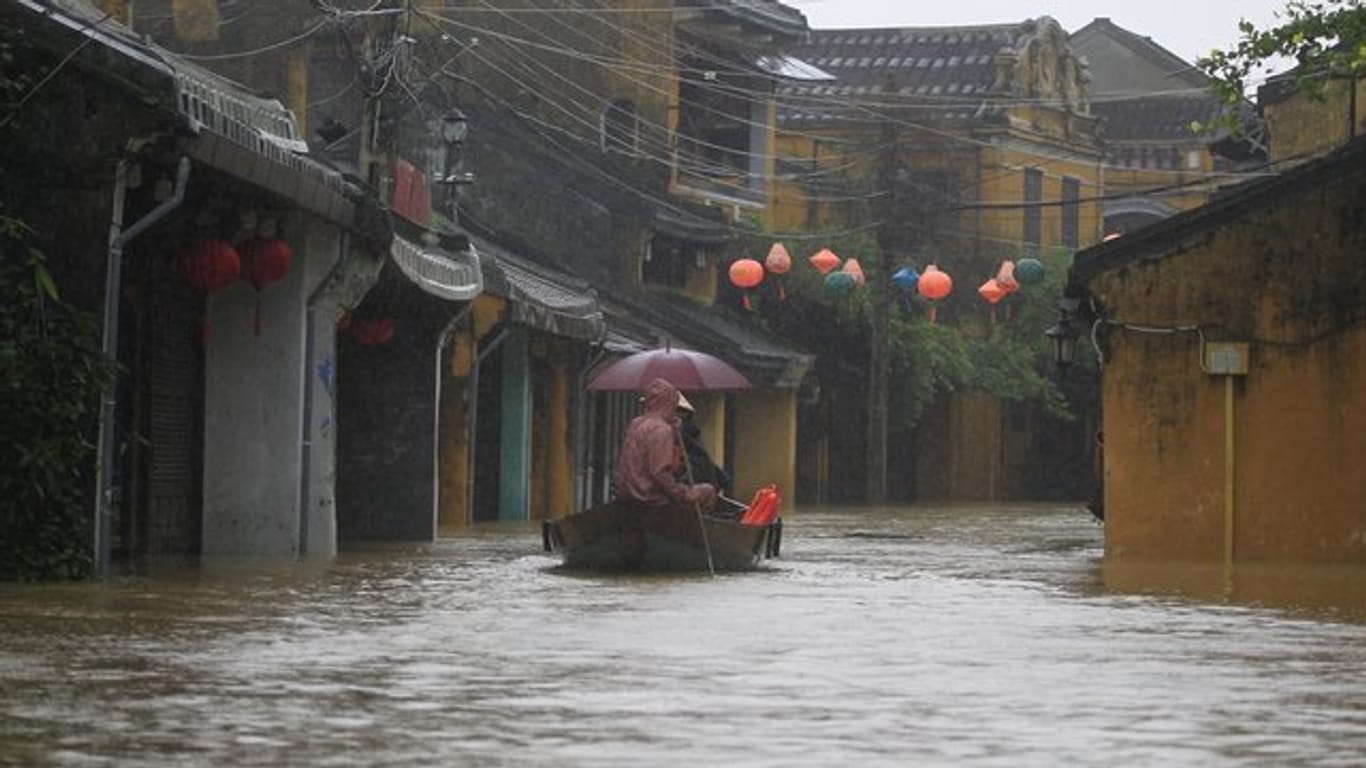Menschen fahren in Hoi An, Vietnam, durch eine überflutete Straße.