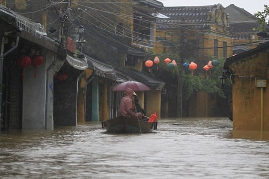 Menschen fahren in Hoi An, Vietnam, durch eine überflutete Straße.