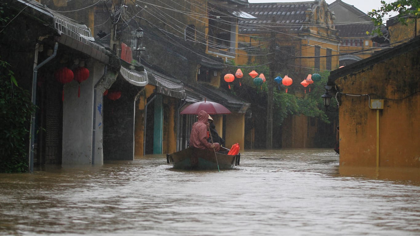 Menschen fahren in Hoi An, Vietnam, durch eine überflutete Straße.