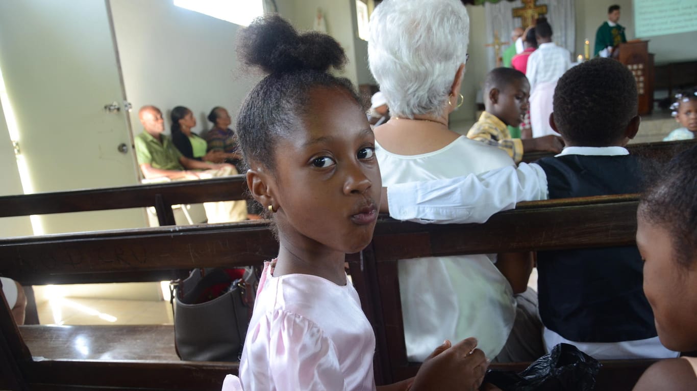 Ein Mädchen aus der jamaikanischen Gemeinde Seaford Town trinkt während des Gottesdienstes einen Schluck Wasser.