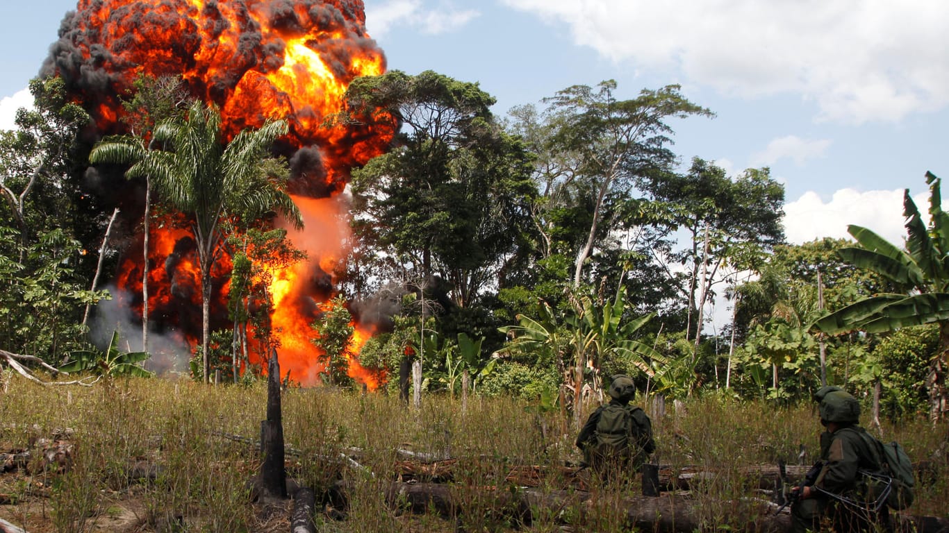 Kolumbianische Polizisten halten 2012 vor einem brennenden Drogenlabor Wache: Der Kampf Kolumbiens gegen die Drogenkartelle ist noch lange nicht vorüber.