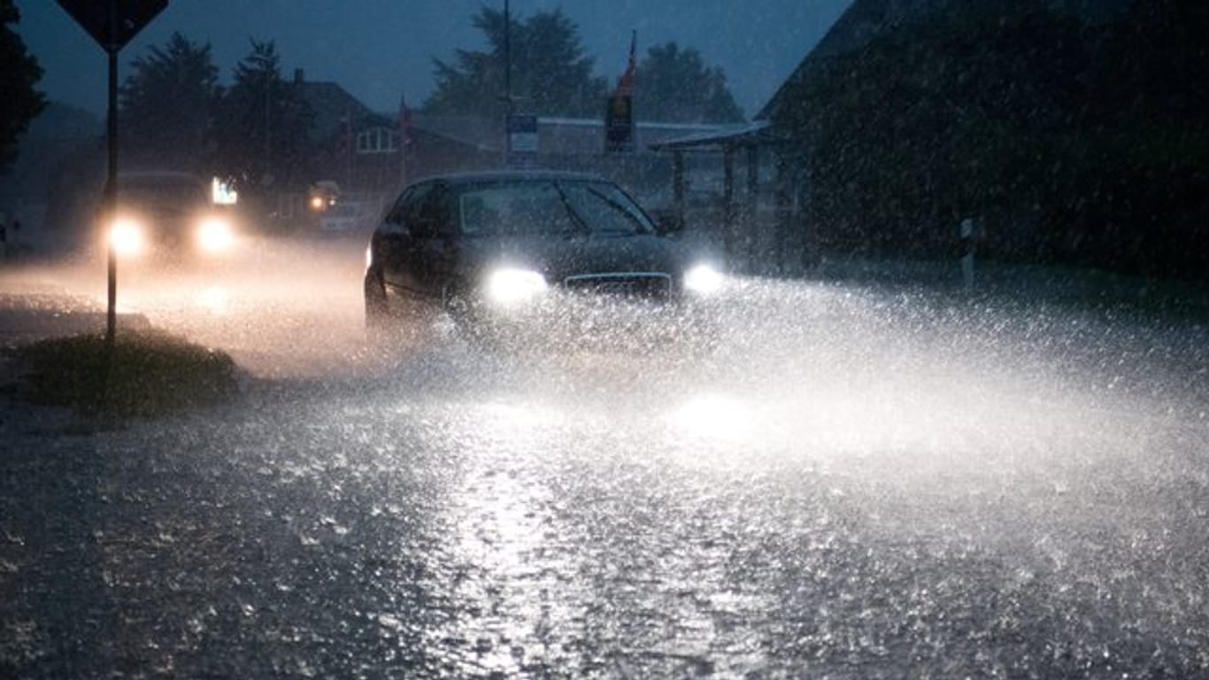 Auto auf einer bei einem schweren Unwetter mit Starkregen überfluteten Straße in Niedersachsen.