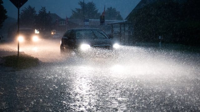 Auto auf einer bei einem schweren Unwetter mit Starkregen überfluteten Straße in Niedersachsen. Auto auf einer bei einem schweren Unwetter mit Starkregen überfluteten Straße in Niedersachsen.
