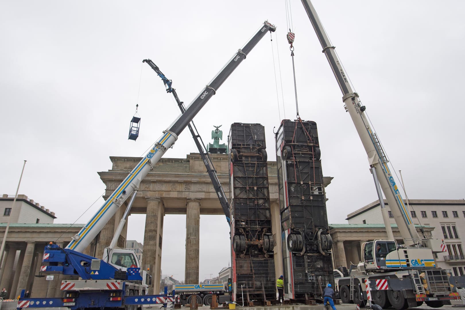 Zwei ausrangierte Busse werden in Berlin vor dem Brandenburger Tor aufgestellt. Sie sind Bestandteil des Monuments des deutsch-syrischen Künstlers Manaf Halbouni.