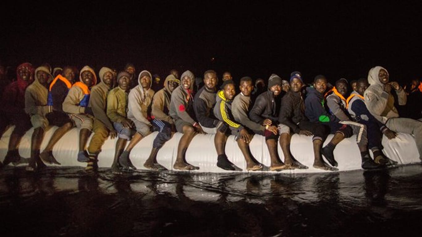 Flüchtlinge aus verschiedenen afrikanischen Staaten sitzen in einem überfüllten Schlauchboot im Mittelmmer vor der libyschen Küste.