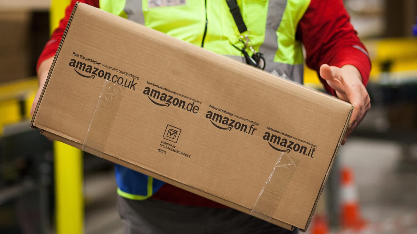 Ein Amazon-Mitarbeiter trägt ein Paket.