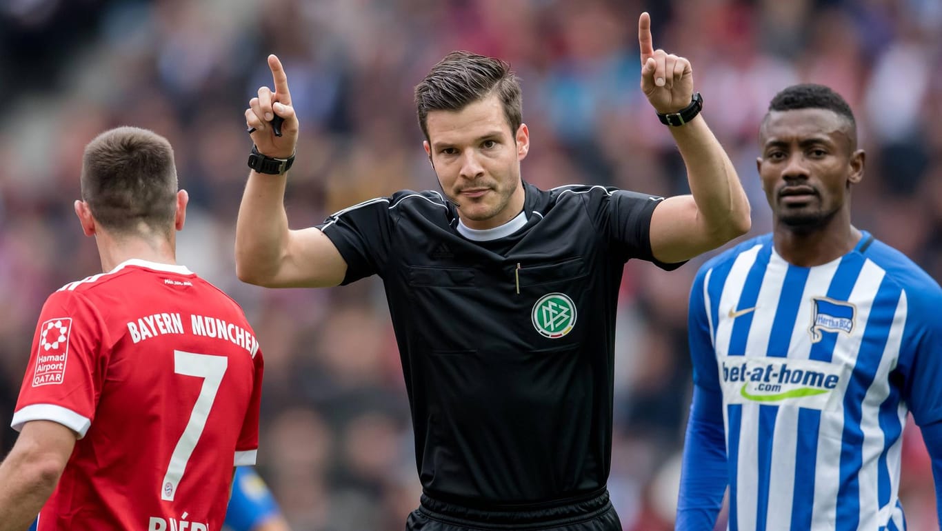 Schiedsrichter Harm Osmers (m.) fordert beim Spiel zwischen Hertha und Bayern den Videobeweis an.